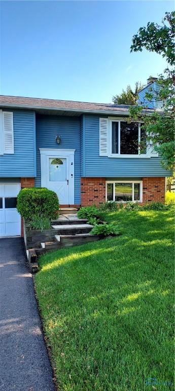 856 Village Pkwy, Waterville, OH 43566 - raised ranch with brick siding, a garage, a front lawn, and driveway