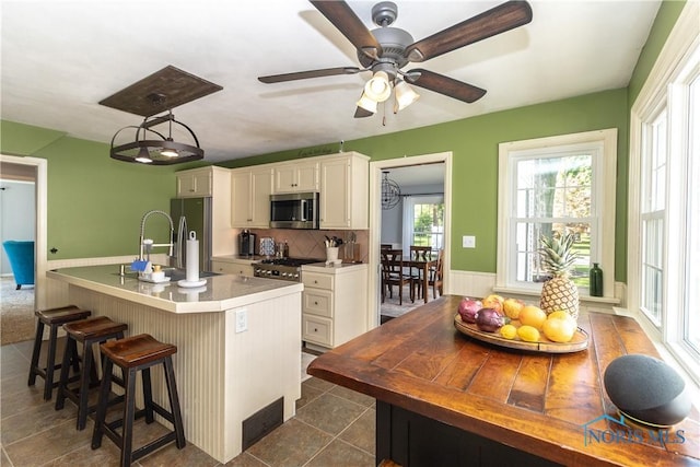 1619 Grant Blvd, Findlay, OH 45840 - kitchen with stainless steel appliances, a kitchen breakfast bar, decorative backsplash, a ceiling fan, and white cabinetry