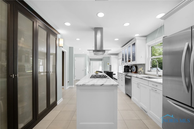 kitchen featuring appliances with stainless steel finishes, a sink, a kitchen island, glass insert cabinets, and island exhaust hood
