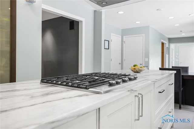 kitchen with light stone countertops, stainless steel gas stovetop, white cabinetry, and recessed lighting