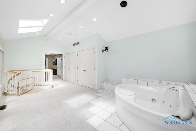bathroom with a skylight, a jetted tub, and recessed lighting