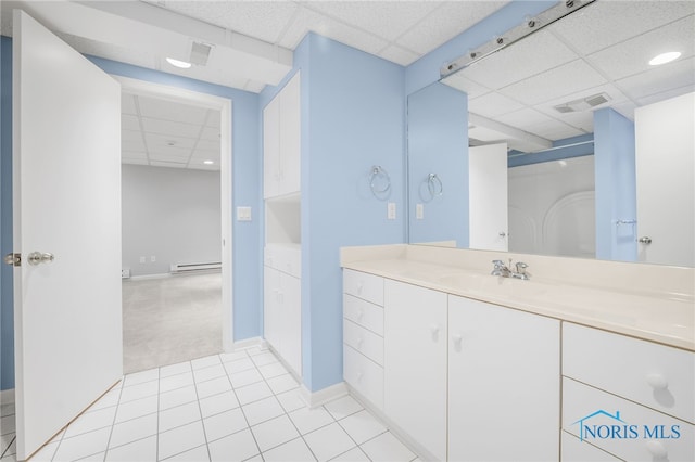 bathroom featuring a drop ceiling, a baseboard radiator, tile patterned floors, vanity, and baseboards