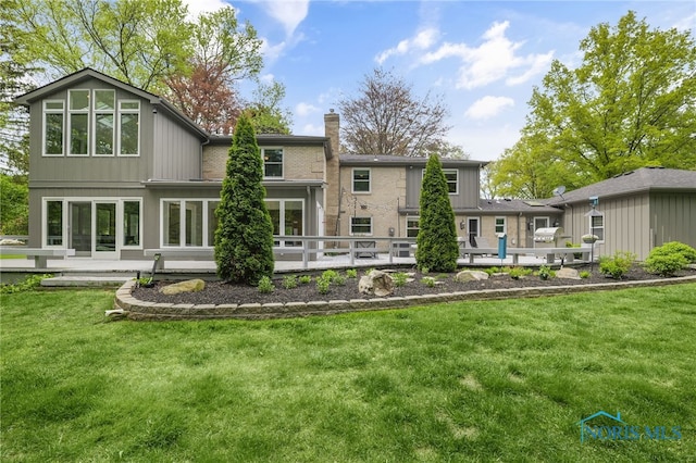 rear view of house with a chimney, a lawn, and a patio area