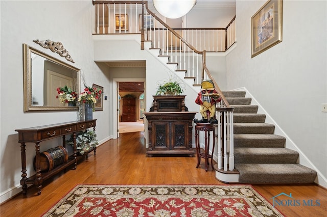 stairway featuring wood finished floors, baseboards, and a towering ceiling