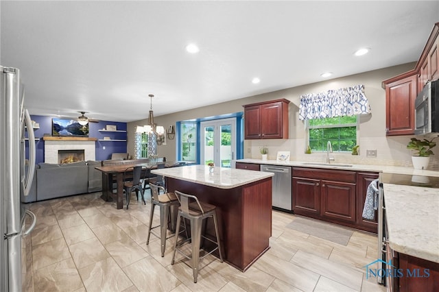 312 Fairmont Dr, Findlay, OH 45840 - kitchen featuring appliances with stainless steel finishes, a sink, a brick fireplace, open floor plan, and a center island