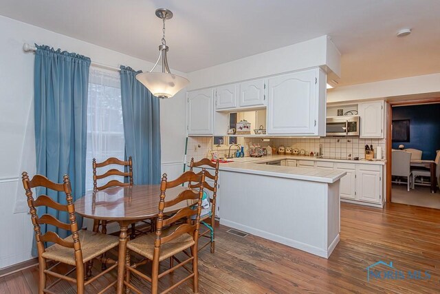 3757 N Mccord Rd, Toledo, OH 43617 - kitchen with stainless steel microwave, a peninsula, white cabinetry, and backsplash