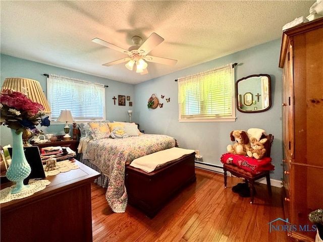 360 N Harmony Dr, Napoleon, OH 43545 - bedroom featuring a baseboard heating unit, hardwood / wood-style flooring, a textured ceiling, and ceiling fan
