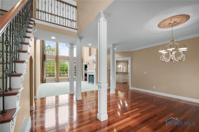 665 Meadowview Dr, Findlay, OH 45840 - unfurnished living room with decorative columns, wood finished floors, crown molding, a fireplace, and stairway