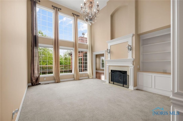 665 Meadowview Dr, Findlay, OH 45840 - unfurnished living room featuring carpet flooring, a chandelier, a fireplace with flush hearth, baseboards, and a towering ceiling