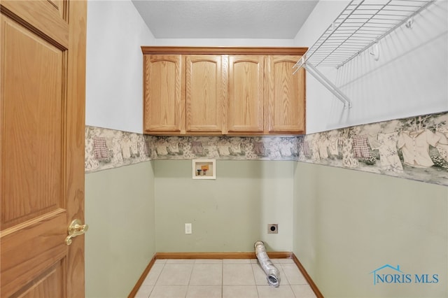 1330 Kennsington Dr, Findlay, OH 45840 - laundry area featuring hookup for an electric dryer, cabinet space, washer hookup, light tile patterned floors, and baseboards