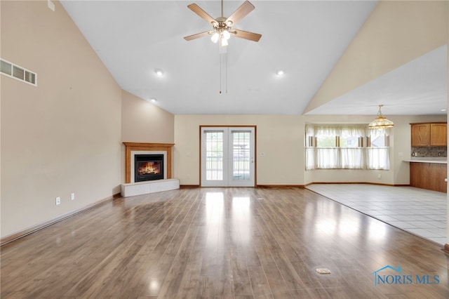 1330 Kennsington Dr, Findlay, OH 45840 - unfurnished living room with high vaulted ceiling, a glass covered fireplace, a ceiling fan, light wood-style flooring, and baseboards