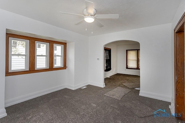 940 Kingston Ave, Toledo, OH 43605 - spare room with arched walkways, dark colored carpet, a ceiling fan, and baseboards