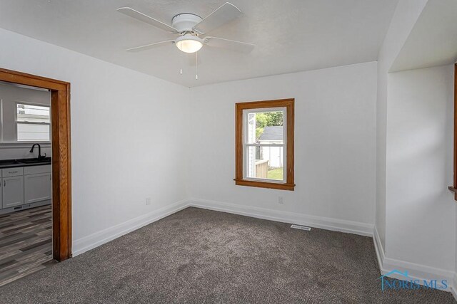 940 Kingston Ave, Toledo, OH 43605 - spare room with dark carpet, baseboards, ceiling fan, and a sink