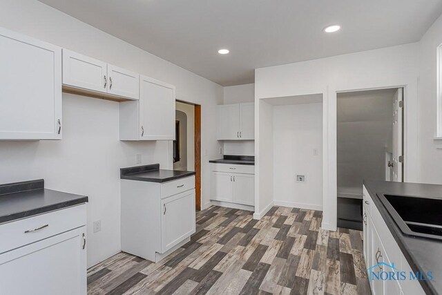 940 Kingston Ave, Toledo, OH 43605 - kitchen with white cabinets, dark countertops, wood finished floors, a sink, and recessed lighting