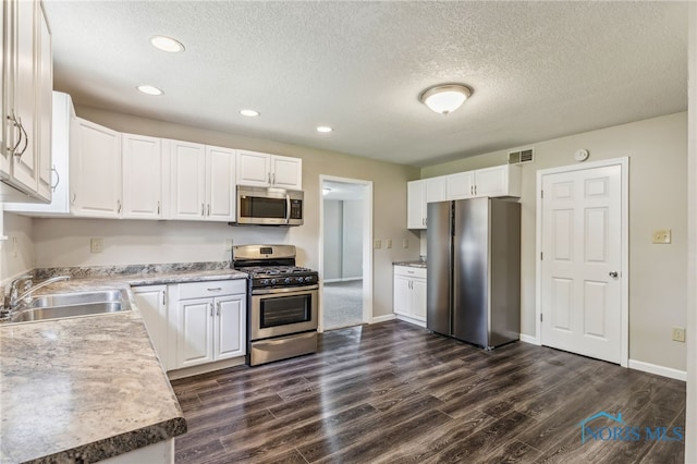 221 Poplar St, North Baltimore, OH 45872 - kitchen with appliances with stainless steel finishes, a sink, dark wood-type flooring, a textured ceiling, and white cabinets