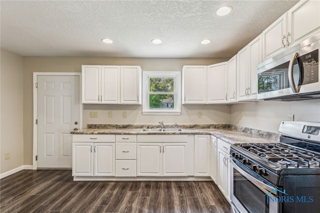 221 Poplar St, North Baltimore, OH 45872 - kitchen featuring stainless steel appliances, a sink, dark wood finished floors, a textured ceiling, and white cabinets