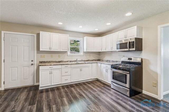221 Poplar St, North Baltimore, OH 45872 - kitchen featuring stainless steel appliances, a sink, dark wood-style floors, white cabinetry, and a textured ceiling