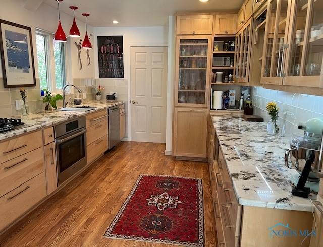28330 W River Rd, Perrysburg, OH 43551 - kitchen with stainless steel appliances, a sink, light brown cabinets, wood finished floors, and tasteful backsplash