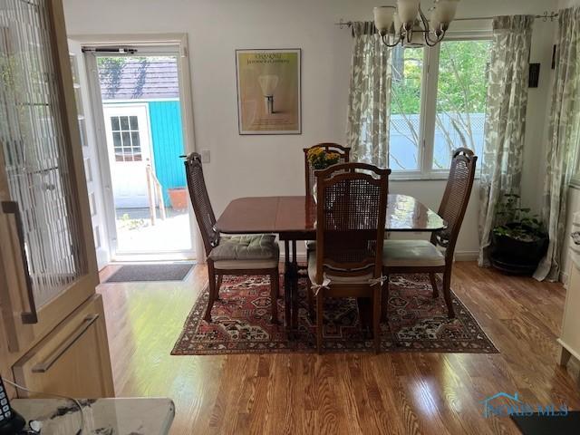 28330 W River Rd, Perrysburg, OH 43551 - dining space featuring a chandelier, wood finished floors, and baseboards