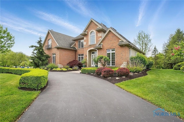 traditional-style home featuring brick siding, a front lawn, and driveway