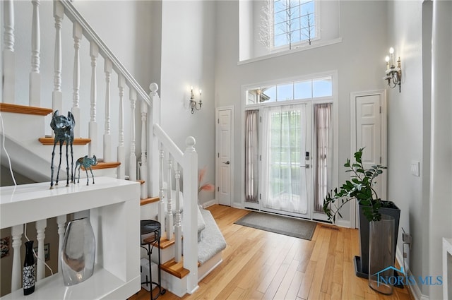 entrance foyer with stairs, a high ceiling, wood finished floors, and baseboards