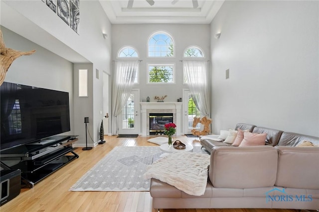 living room featuring a glass covered fireplace, wood finished floors, and a towering ceiling