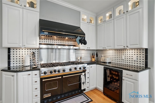 kitchen featuring wine cooler, double oven range, dark countertops, decorative backsplash, and white cabinets