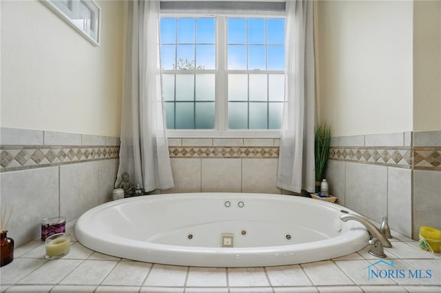 bathroom with tile walls, a tub with jets, healthy amount of natural light, and a wainscoted wall