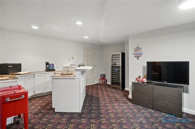 kitchen with beverage cooler, dark carpet, white cabinets, recessed lighting, and a peninsula