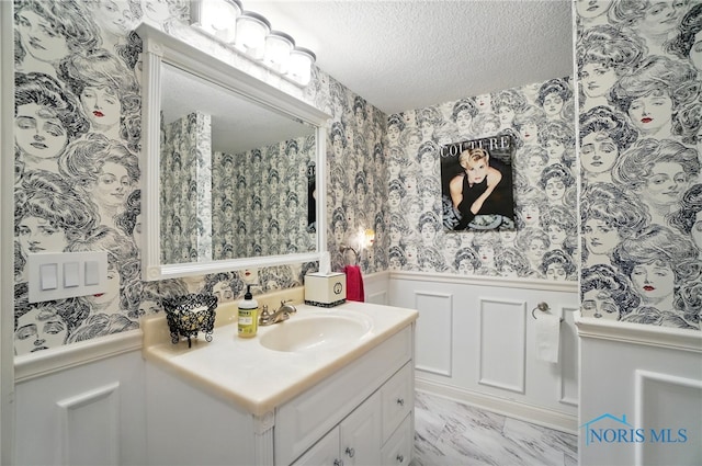 bathroom with a wainscoted wall, wallpapered walls, a decorative wall, vanity, and marble finish floors