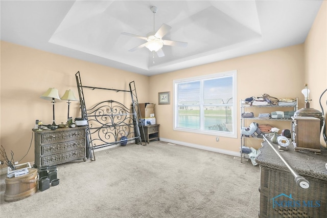bedroom with a raised ceiling, carpet floors, baseboards, and ceiling fan