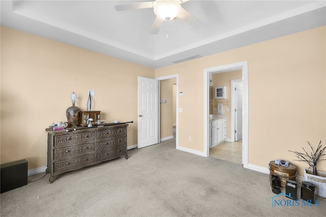 bedroom featuring carpet floors, a tray ceiling, baseboards, and ceiling fan