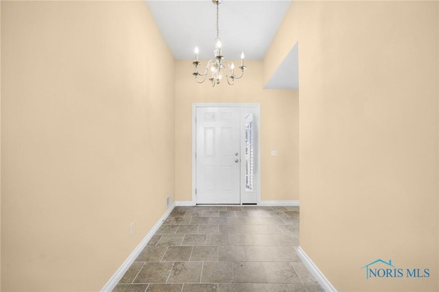 foyer with a chandelier, baseboards, and stone finish flooring