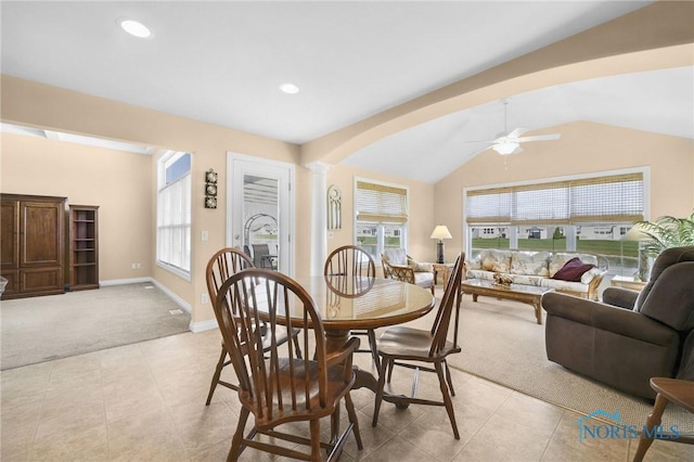 dining room featuring light colored carpet, lofted ceiling, plenty of natural light, a ceiling fan, and arched walkways