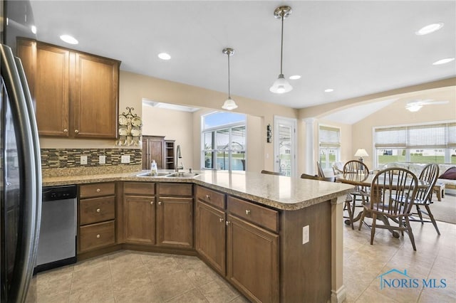 kitchen with stainless steel appliances, a peninsula, a sink, tasteful backsplash, and light tile patterned floors