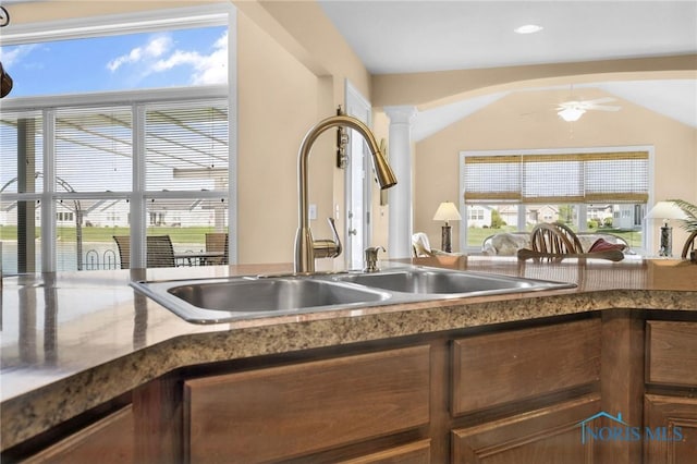 kitchen with a sink, decorative columns, vaulted ceiling, and a ceiling fan
