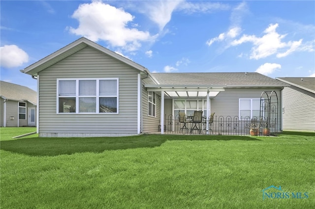 rear view of property with a patio and a lawn