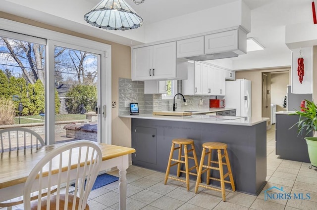 4426 Sheraton Rd, Ottawa Hills, OH 43615 - kitchen featuring white fridge with ice dispenser, light tile patterned floors, a peninsula, and light countertops