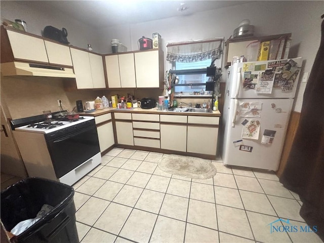 908 Mckinley Ave, Toledo, OH 43605 - kitchen with white appliances, under cabinet range hood, a sink, light tile patterned floors, and white cabinets