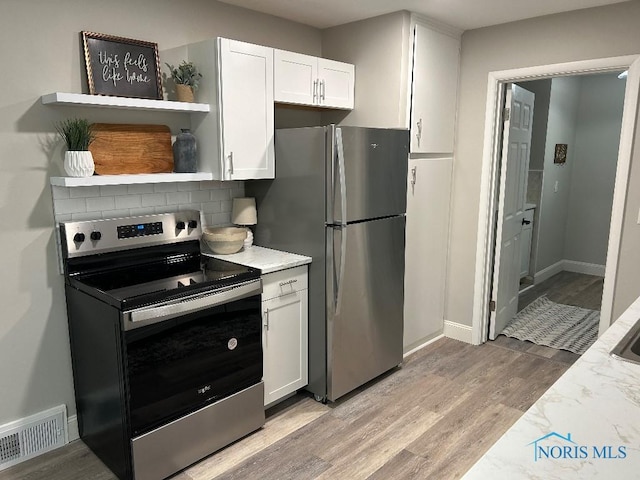 613 W Yeasting St, Gibsonburg, OH 43431 - kitchen with stainless steel appliances, white cabinetry, light wood-style flooring, light stone counters, and baseboards
