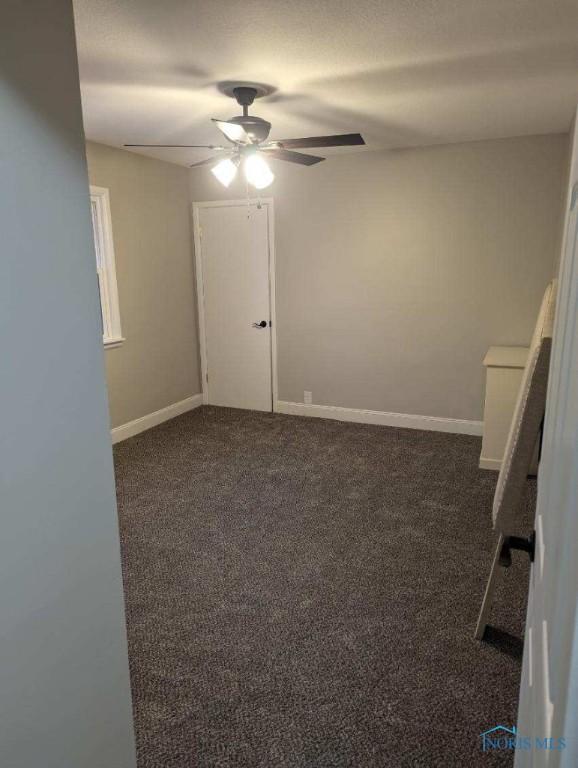 613 W Yeasting St, Gibsonburg, OH 43431 - spare room with a ceiling fan, dark carpet, and baseboards