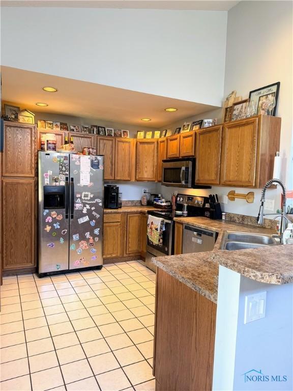 801 W Sandusky St, Findlay, OH 45840 - kitchen featuring stainless steel appliances, a sink, brown cabinetry, light tile patterned flooring, and a peninsula
