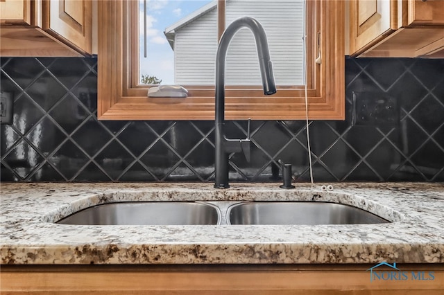 1977 Lexington Dr, Perrysburg, OH 43551 - kitchen view of a sink, light stone countertops, backsplash, and brown cabinetry