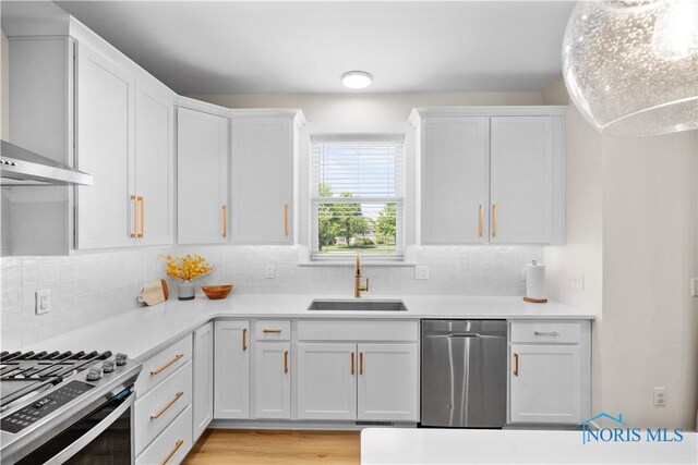 5653 Mallard Pointe Ln, Sylvania, OH 43560 - kitchen with appliances with stainless steel finishes, a sink, wall chimney range hood, and white cabinets