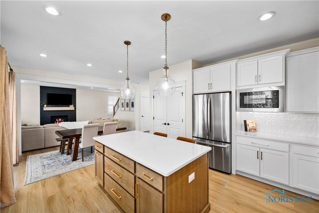 5653 Mallard Pointe Ln, Sylvania, OH 43560 - kitchen with freestanding refrigerator, built in microwave, a center island, white cabinetry, and light wood-type flooring