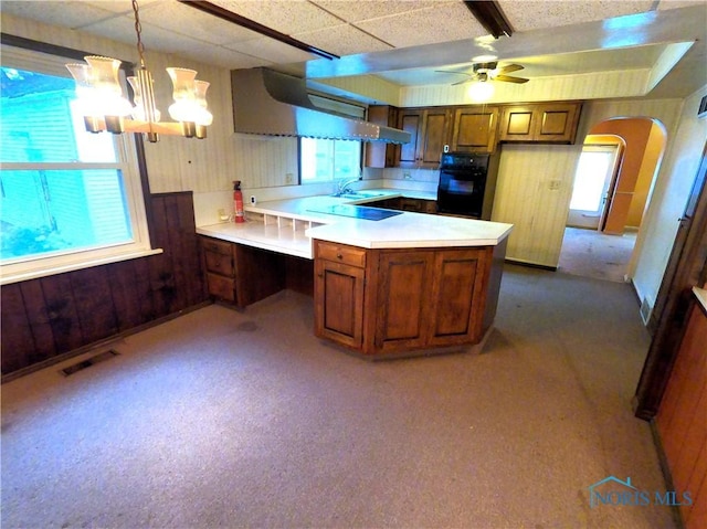 651 Park St, Napoleon, OH 43545 - kitchen featuring black appliances, brown cabinetry, arched walkways, wooden walls, and exhaust hood