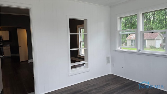 103 E N St, Liberty Center, OH 43532 - spare room featuring crown molding, plenty of natural light, and dark wood-type flooring
