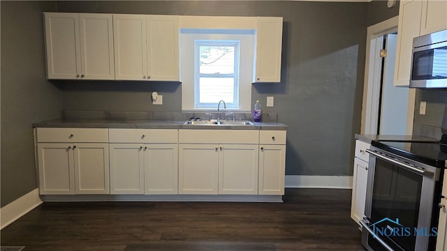 103 E N St, Liberty Center, OH 43532 - kitchen with appliances with stainless steel finishes, a sink, white cabinetry, and baseboards