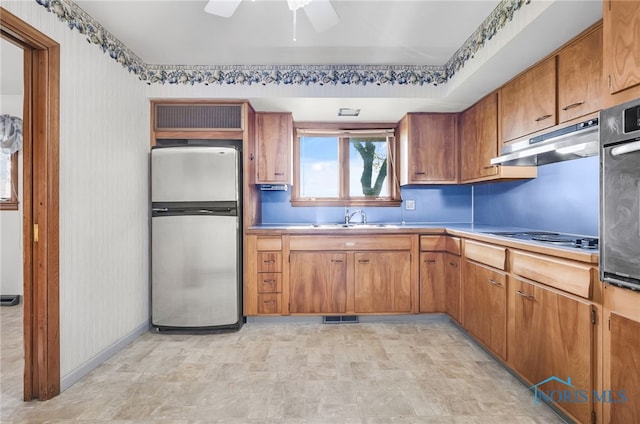 403 S N Curtice Rd, Oregon, OH 43616 - kitchen with appliances with stainless steel finishes, under cabinet range hood, a sink, brown cabinets, and a ceiling fan