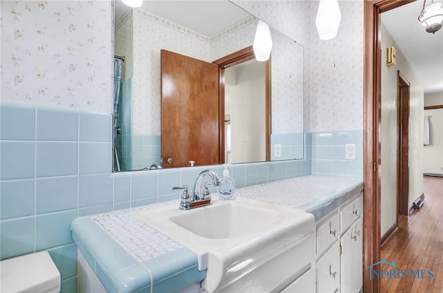 403 S N Curtice Rd, Oregon, OH 43616 - bathroom with wallpapered walls, wood finished floors, a wainscoted wall, tile walls, and vanity
